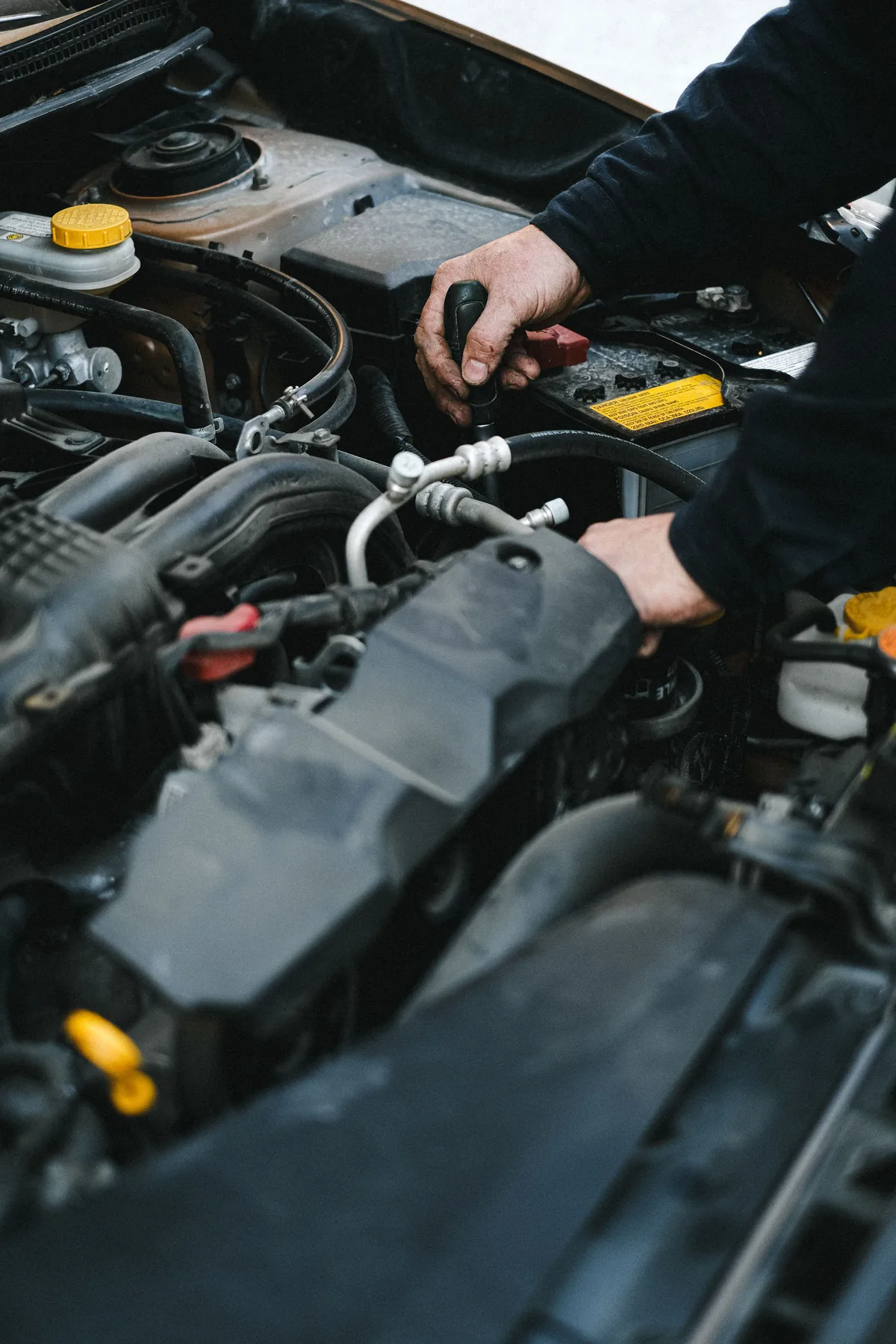 Nahaufnahme von Händen bei der Arbeit an einem Motor; illustrative Stockfotografie